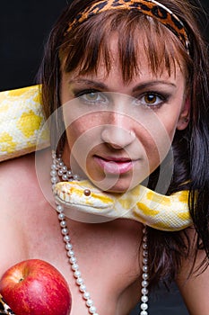 Woman with a snake eating red apple