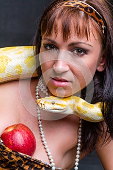 Woman with a snake holding red apple