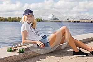 Woman with snapback leaning against longboard