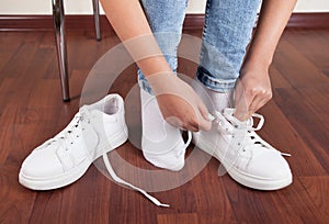 Woman sneakers is tying her shoelaces. Shoes for sports