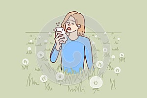 Woman sneezes because of allergy caused by dandelion blossoms and pollen from summer plants