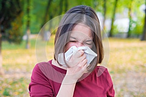 Woman sneezing in a kleenex because of cold and flu