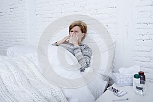 woman with sneezing nose blowing in tissue on bed suffering cold flu virus symptoms having medicines tablets pills