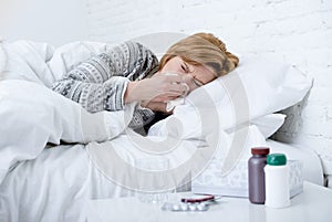 woman with sneezing nose blowing in tissue on bed suffering cold flu virus symptoms having medicines tablets pills