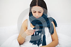 Woman with sneezing nose using tissue on bed suffering cold flu