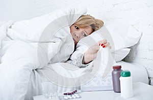 woman with sneezing nose using tissue on bed suffering cold flu virus having medicines