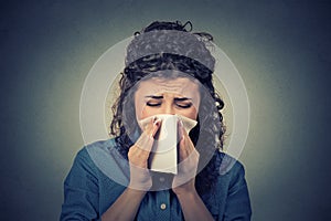 Woman sneezing in a tissue blowing her runny nose photo