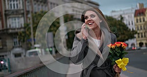 Woman sniffing flowers while speaking over the phone