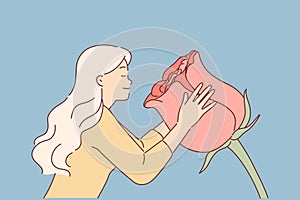 Woman sniffs huge rose flower, enjoying aroma of spring-blooming plant used to create perfume