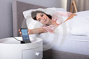 Woman Snoozing Alarm On Mobile Phone photo
