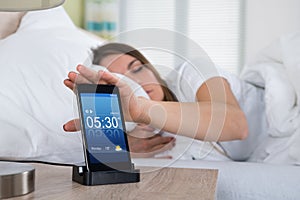 Woman Snoozing Alarm On Mobile Phone Screen photo