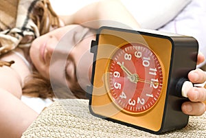 Woman snoozing a red alarm clock photo