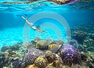 A woman snorkeling in the beautiful coral reef with lots of fish