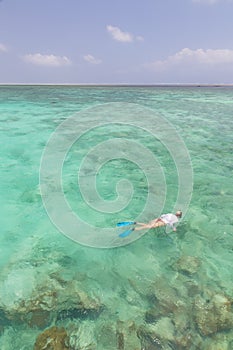 Woman snorkeling in clear shallow sea of tropical lagoon with turquoise blue water.