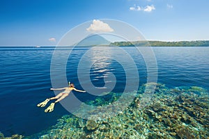 Woman snorkeling in clear tropical waters on a background of isl