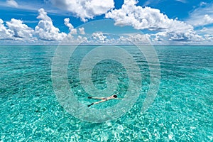 Woman snorkeling in clear tropical waters in front of exotic island