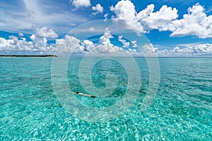 Woman snorkeling in clear tropical waters in front of exotic island