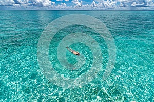 Woman snorkeling in clear tropical waters in front of exotic island