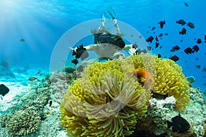 Woman snorkeling with a clownfish in the Indian Ocean