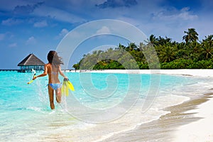 Woman with snorkeling gear running into the waters of the Maldives