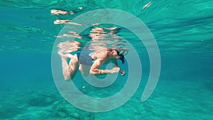 Woman snorkeling, swimming under the water. Freediving at the depth of the sea.