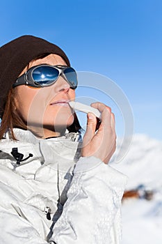 Woman in the snow applying a lipstick protector