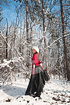 Woman in snow forest in skirt,  fur cap and red sweater