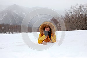 Woman in the snow white with snowing in the forest and mountain background.