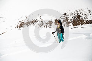 Woman snowboarder on the background of snow-capped mountains and cloudy sky.