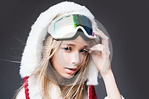 Woman snowboarder in ski clothing poses with a ski goggles. Portrait of young girl with snow goggles.