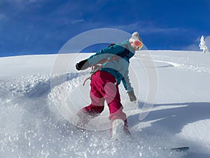 Woman on snowboarding vacation in Alps smiles while shredding champagne powder.