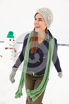 Woman, snowman and smile in nature on vacation with thinking, clothes and adventure in cold. Person, snow sculpture and