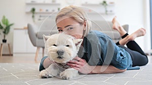 Woman snuggling cute pet's head on floor near sofa indoors