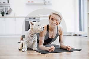 Woman snuggling to little dog while holding Phalakasana II