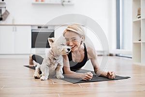 Woman snuggling to little dog while holding Phalakasana II