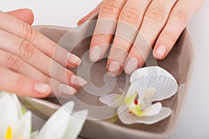 Woman Soaking Hands In Water At Beauty Salon photo