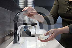 Woman with soap bar washing hands in bathroom, closeup