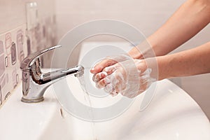 A woman is soaping her hands with soap. Hygiene. Washing hands in the bathroom.