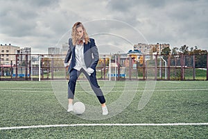 Woman soccer player on the stadium field performs dribbling feint with the ball. concept office manager resting on lunch break