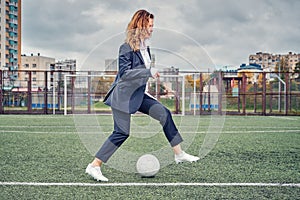 Woman soccer player on the stadium field performs dribbling feint with the ball. concept office manager resting on lunch break