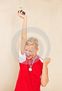 Woman, soccer player and trophy or a winner celebrate on a plain background for football achievement. A young female