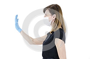 Woman social distancing from corona virus covid-19 wearing a protective white face mask and medical gloves holding up hand saying