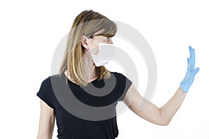 Woman social distancing from corona virus covid-19 wearing a protective white face mask and medical gloves holding up hand saying
