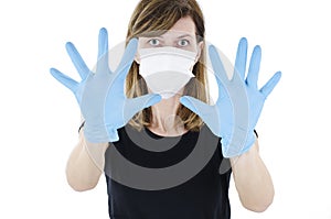 Woman social distancing from corona virus covid-19 wearing a protective white face mask and medical gloves holding up hands