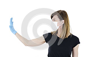 Woman social distancing wearing a protective white face mask and medical gloves holding up hand saying stop.