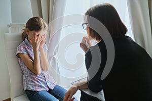 Woman social worker psychologist talking to girl child in office