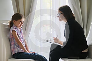 Woman social worker psychologist talking to girl child in office