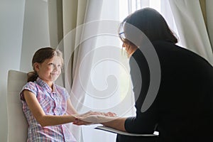 Woman social worker psychologist talking to girl child in office