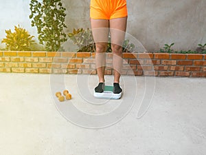 Woman with socks weighing herself on a scale. Lose weight concept. Scale measuring kilograms. Diet