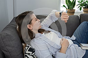 Woman on sofa at home looking at her smart watch. Fatigue and sleep disorder concept